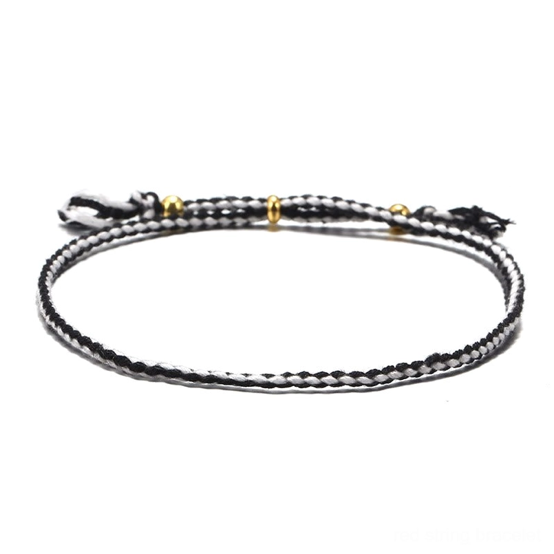 Handmade Tibetan braided rope tassel bracelet in black and white tones for spiritual protection