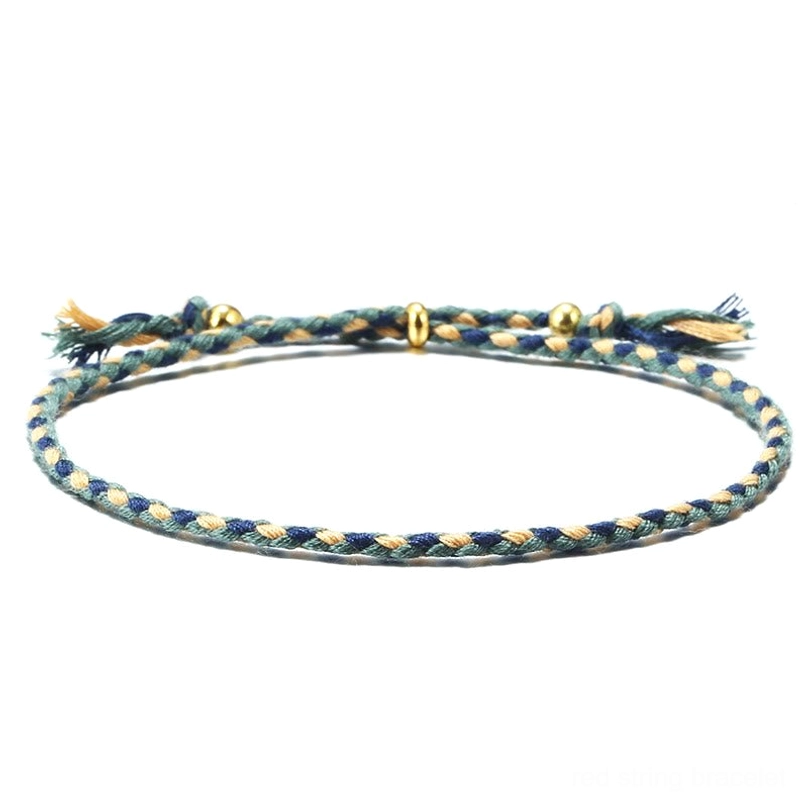 Handmade Tibetan braided rope tassel bracelet in blue-green tones with gold copper spacer beads - flat lay view