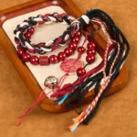 Tibetan cinnabar mountain ghost red string protection bracelet flat lay on wooden tray