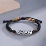 Top down flat lay of Tibetan braided lucky red string bracelet with copper auspicious cloud charm