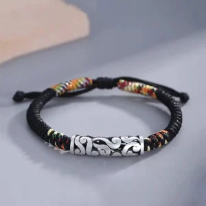 Top down flat lay of Tibetan braided lucky red string bracelet with copper auspicious cloud charm