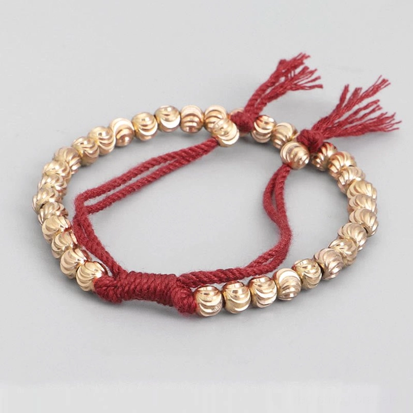 Handmade tibetan copper bead bracelet with red cotton cord angled view showing detail