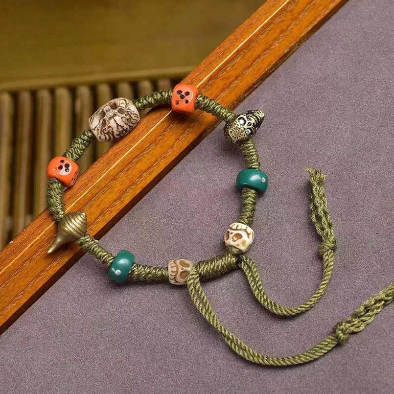 Side view of adjustable Tibetan dragon dice rope bracelet on wooden strip
