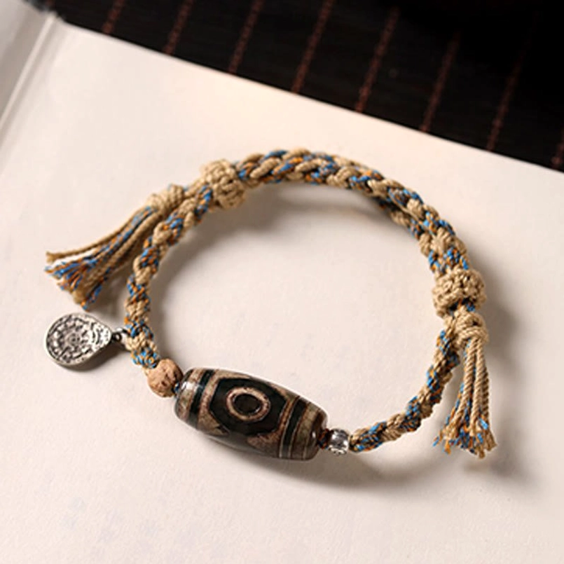 Flat lay view of Tibetan Dzi Bead braided red string bracelet on white desk