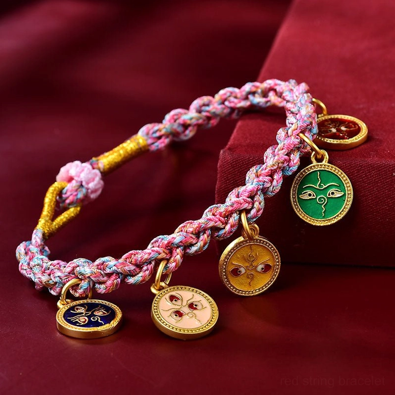 Three quarter close up of Tibetan five gods of wealth multicolor braided lucky string bracelet on red velvet background
