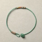Tibetan handmade green aventurine braided bracelet with woven rope and beaded details on light background