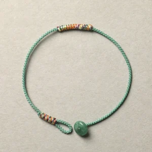 Tibetan handmade green aventurine braided bracelet with woven rope and beaded details on light background