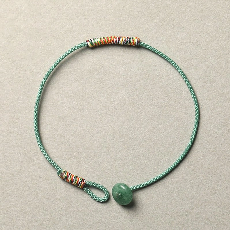 Tibetan handmade green aventurine braided bracelet with woven rope and beaded details on light background
