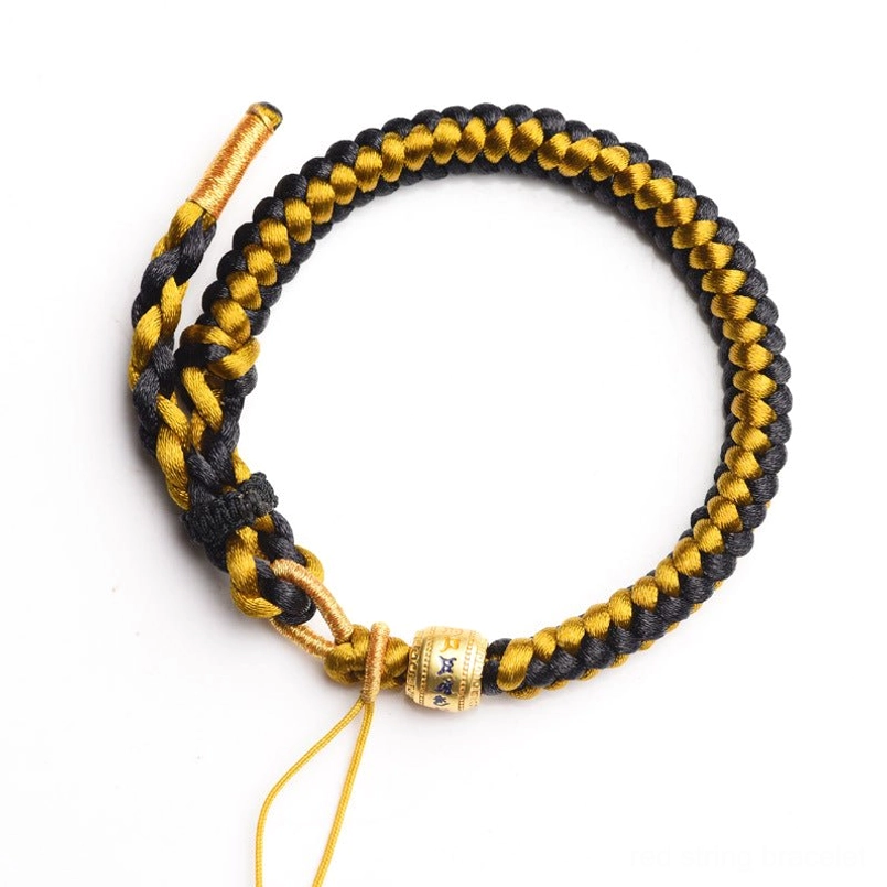 Hand-braided Tibetan Om Mani Padme Hum bracelet overhead flat lay with inscribed metal bead and loose ends