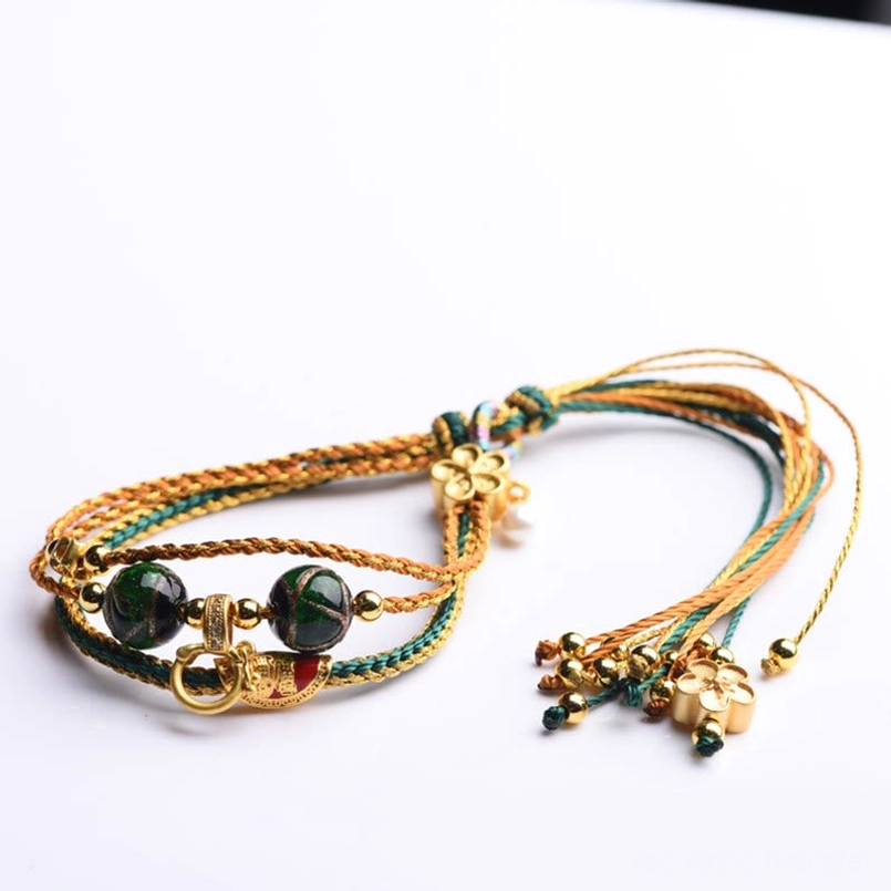 Handmade tibetan braided healing bracelet with tassel and gold metal buckles on white background