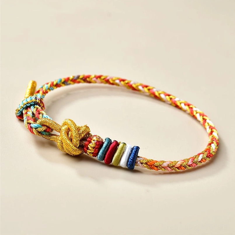 Front oblique view of Tibetan healing red string bracelet with central gold decorative knot