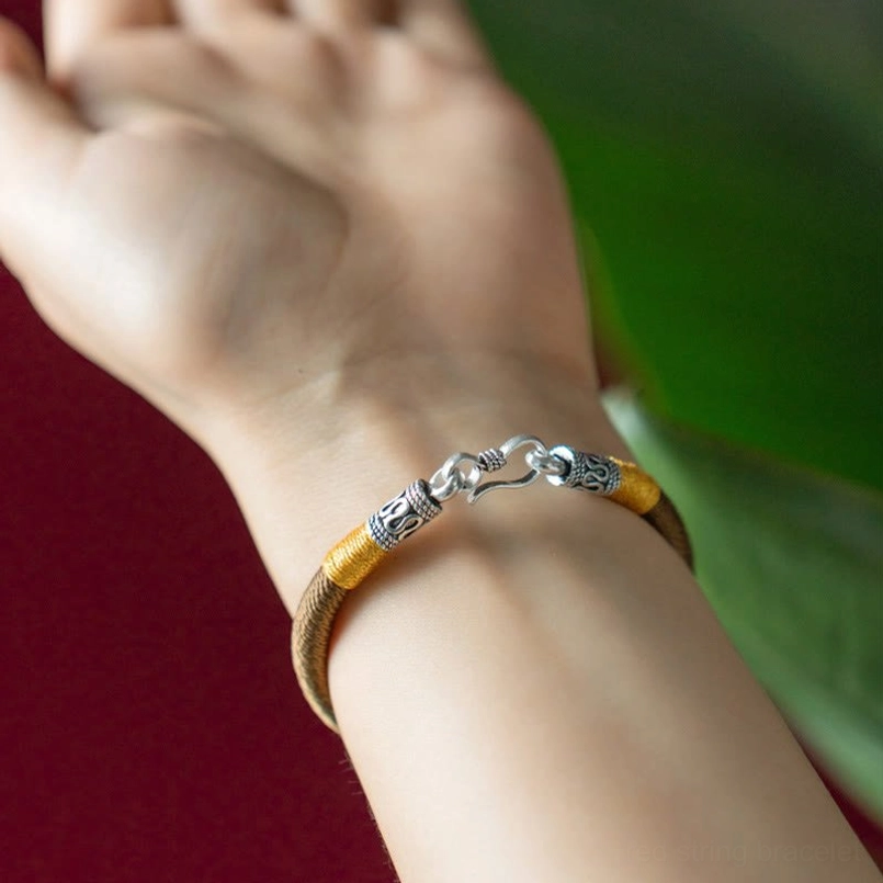 Tibetan style thin woven bracelet with yellow cord accents and silver metal hardware