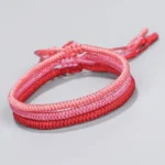 Tibetan King Kong knot braided bracelet gradient red-pink cord on light gray background frontal view