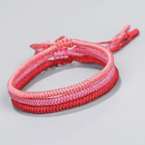 Tibetan King Kong knot braided bracelet gradient red-pink cord on light gray background frontal view