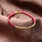 Tibetan King Kong Knot red string bracelet with multicolor woven segment, close-up top view showing adjustable braided tail