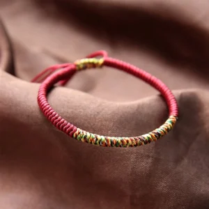 Tibetan King Kong Knot red string bracelet with multicolor woven segment, close-up top view showing adjustable braided tail