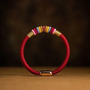 Tibetan King Kong Knot red string bracelet with gold magnetic buckle and colorful woven accents on wooden surface