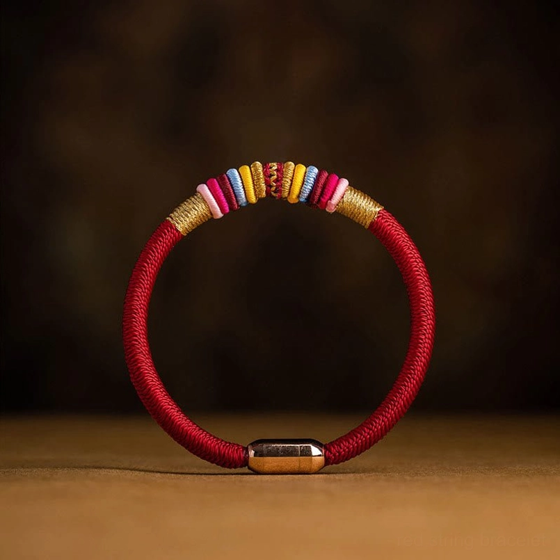 Tibetan King Kong Knot red string bracelet with gold magnetic buckle and colorful woven accents on wooden surface