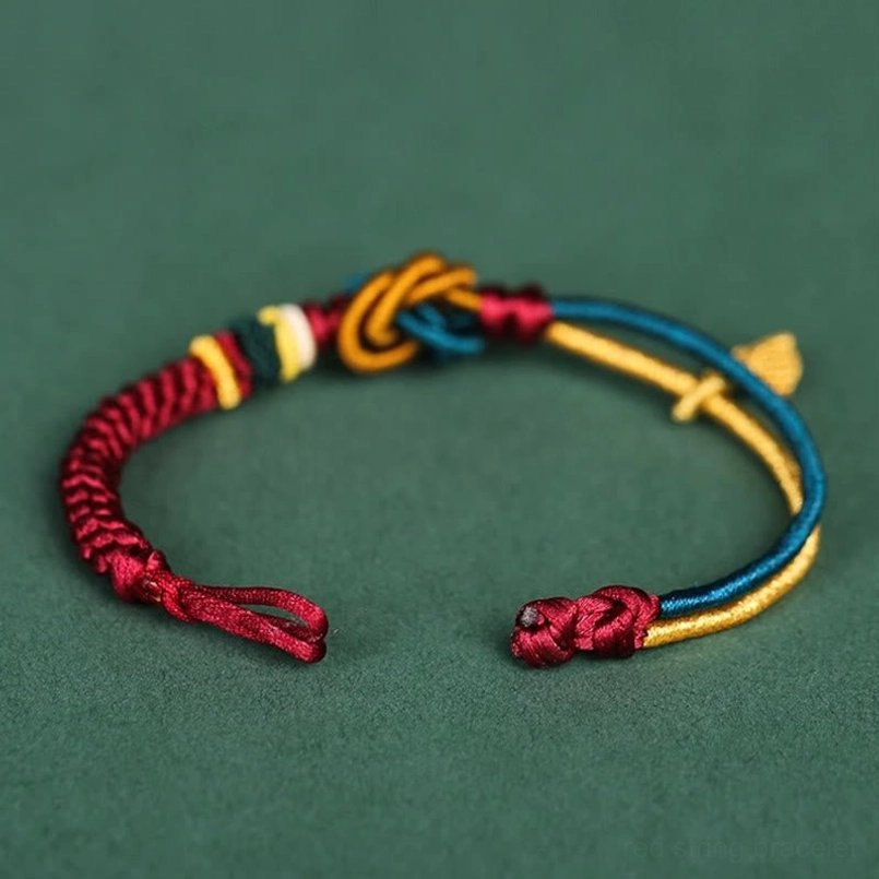 Top-down view of handmade braided luck bracelet showing adjustable ends and mixed color knots