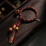 Tibetan koi fish red string bracelet with 925 sterling silver charms and beads displayed on dark wooden tray