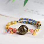 Tibetan lacquer bead tiger eye stone protection red string bracelet top view on light desk