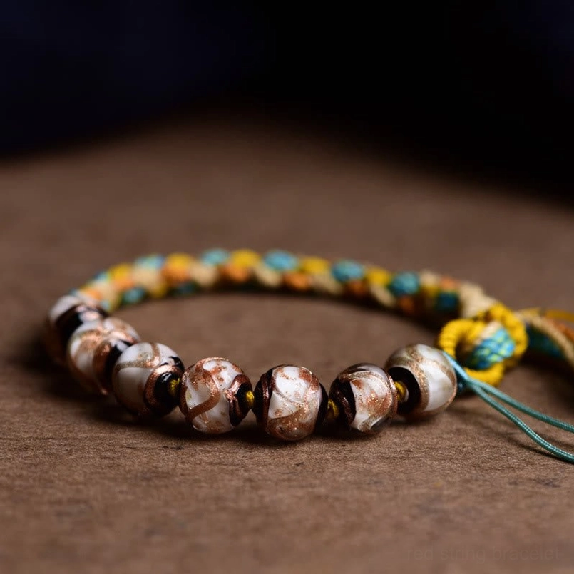 Close-up detailed view of Tibetan glass bead texture with multi-color braided cord