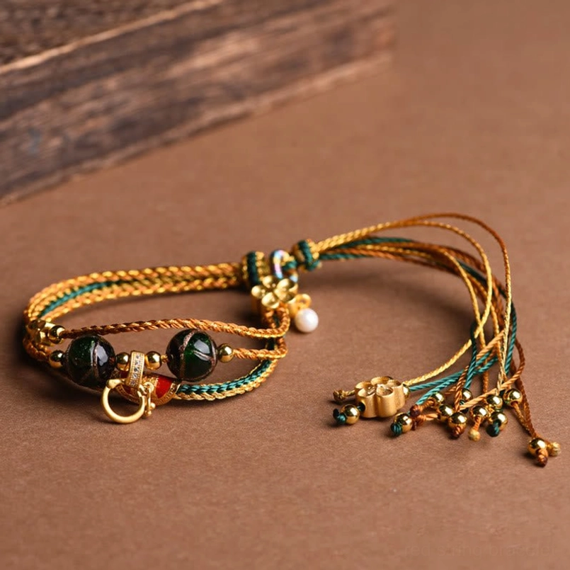 Tibetan liuli glass bracelet with hanging gold buckle and tassel pendants detail view