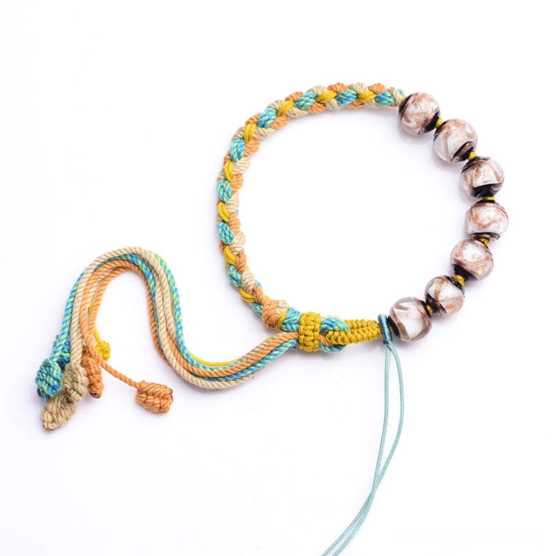 Flat laid Tibetan Liuli glass bracelet with marbled brown beads and braided sacred string