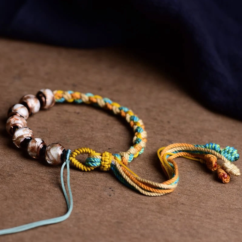 Side view of Tibetan glass spiritual bracelet with gradient braided rope and extended cord ends