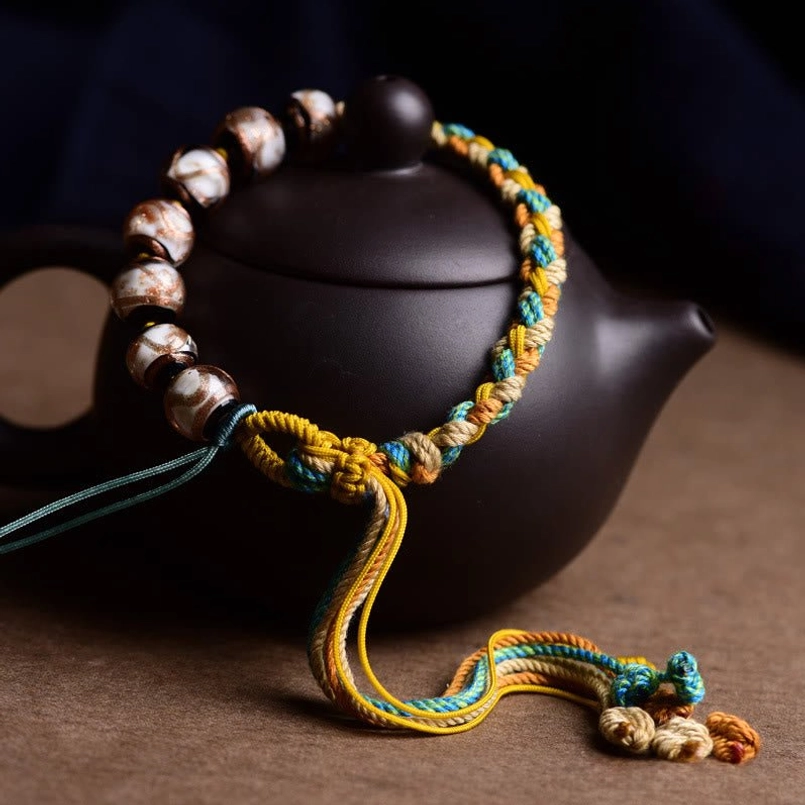 Top-down view of Tibetan glass bead health bracelet with woven rope and glazed stone beads