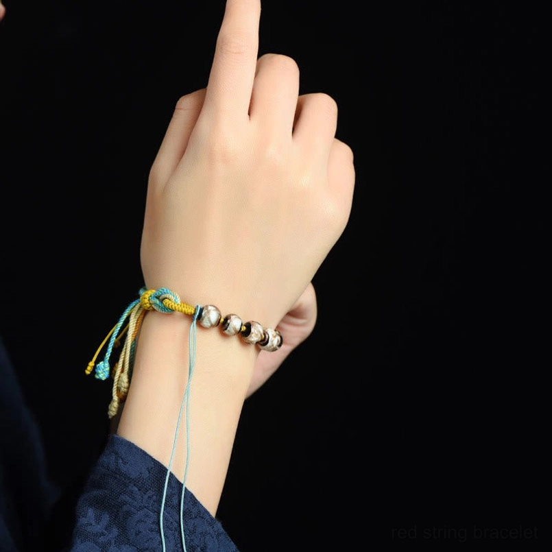 Tibetan Liuli glass bracelet worn on left wrist with metal spacer beads and colorful woven tail