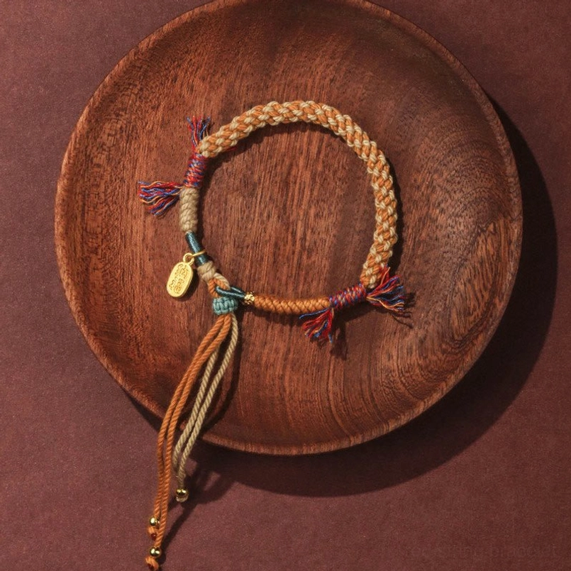 Side view of Tibetan colored string bracelet with tassels and fortune charm