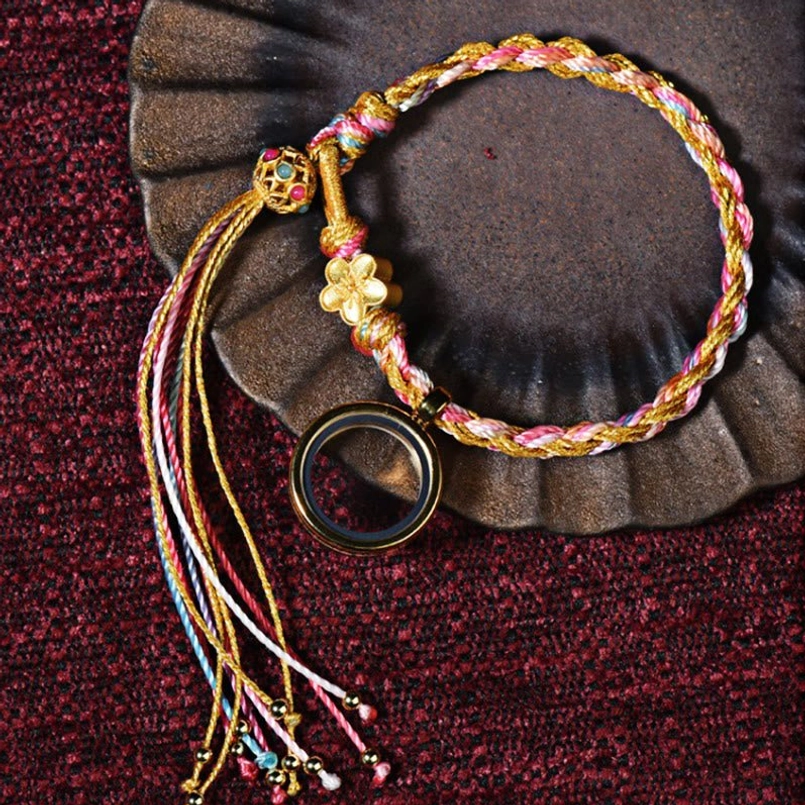 Tibetan lucky braided string bracelet with colorful cord, metal flower and circular pendant with tassel displayed with vintage metal censer