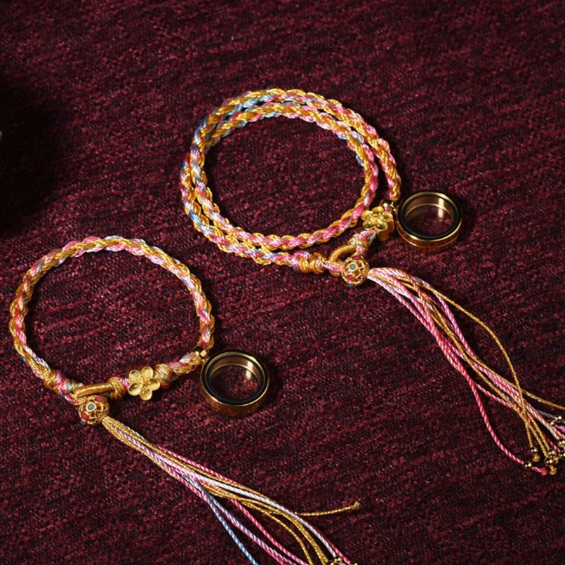 Two Tibetan handmade braided lucky string bracelets with pastel colors and gold braid showing metal ring pendants and tassel details