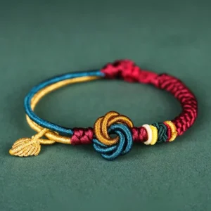 Tibetan mandala knot leaf bracelet handmade flat lay with golden charm on dark green background
