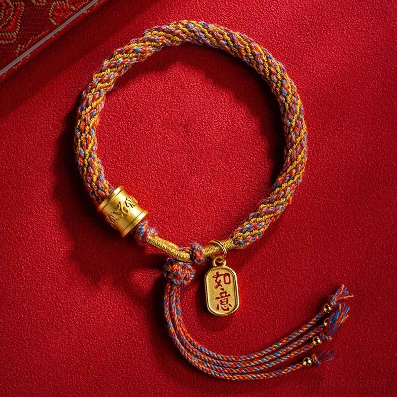 Tibetan Om Mani Padme Hum Ruyi multicolor braided bracelet flat lay with gold charms on red fabric