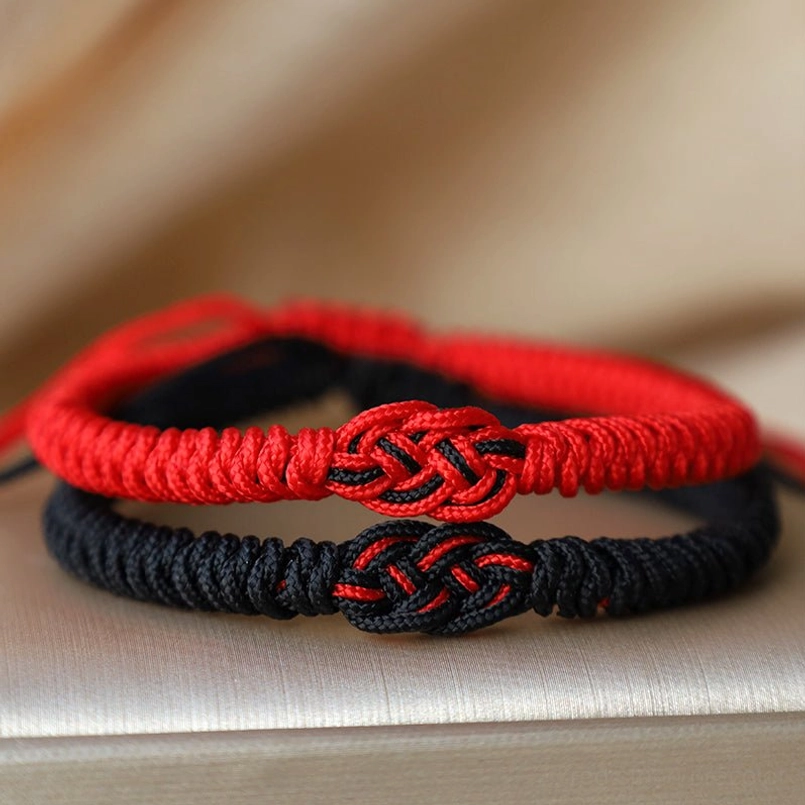 Close-up detail of red and black woven Chinese knot bracelet with adjustable knot closure