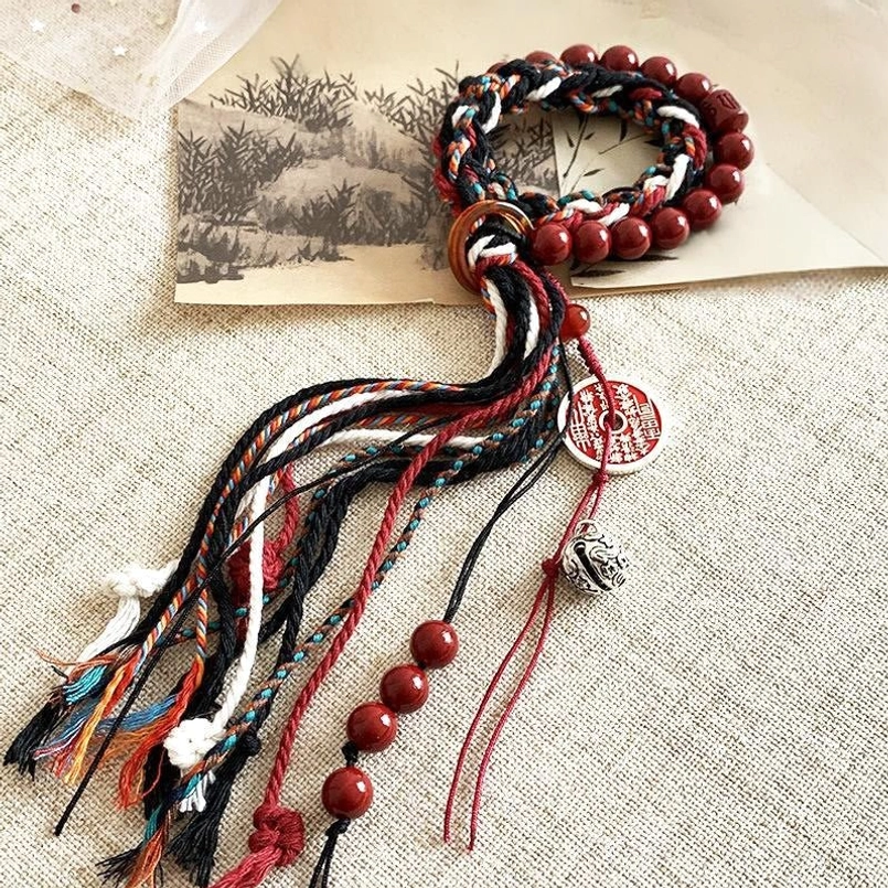 Tibetan cinnabar tassel red string bracelet placed on vintage print background