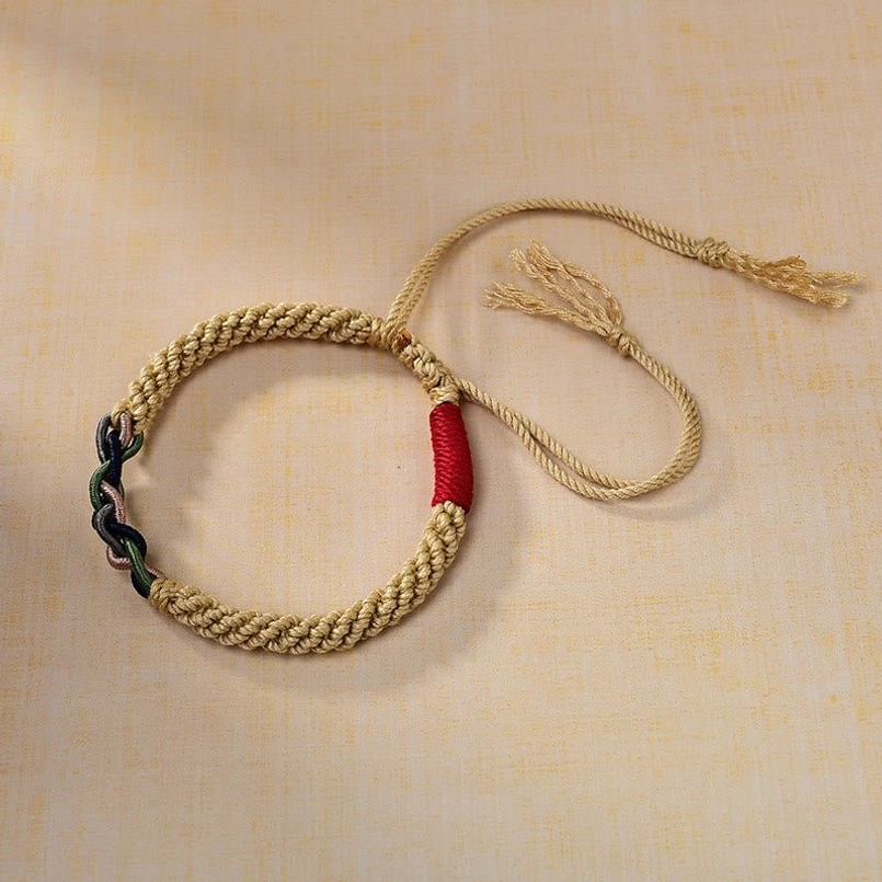 Side overhead view of Tibetan cotton rope bracelet with protective red cord segment and traditional knotwork detail