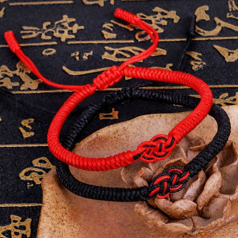 Tibetan red string Chinese knot bracelets on calligraphy patterned background showing traditional design