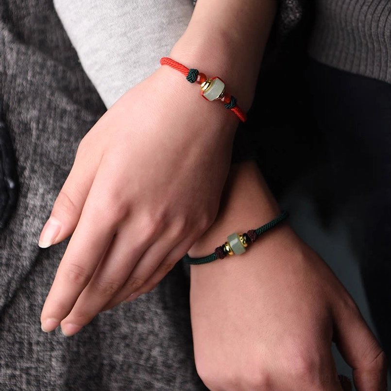 Woman wearing red and dark green tibetan braided string bracelets with jade and gold bead details on wrist