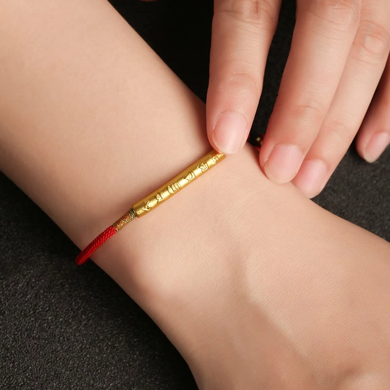 Lifestyle photo of Tibetan Om Mani Padme Hum red string bracelet worn on left wrist with gold mantra tube