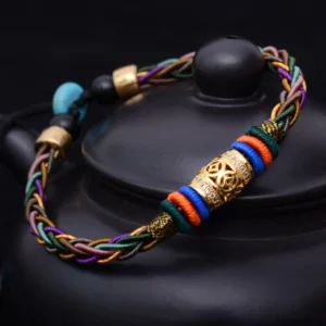 Tibetan handmade eight knot red string bracelet with copper coin displayed on black teapot