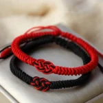 Couple Tibetan red string protection bracelets with black and red Chinese knots on light background