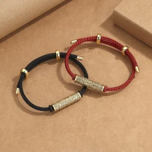 Tibetan handcrafted red and black string protection bracelets with gold and silver metal charms on kraft paper
