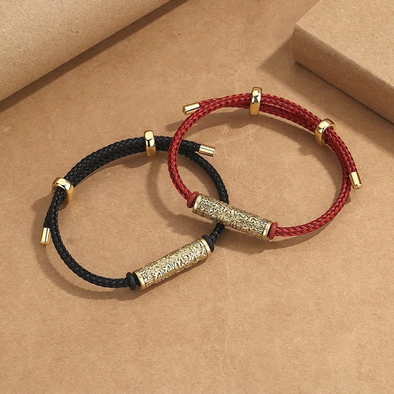 Tibetan handcrafted red and black string protection bracelets with gold and silver metal charms on kraft paper