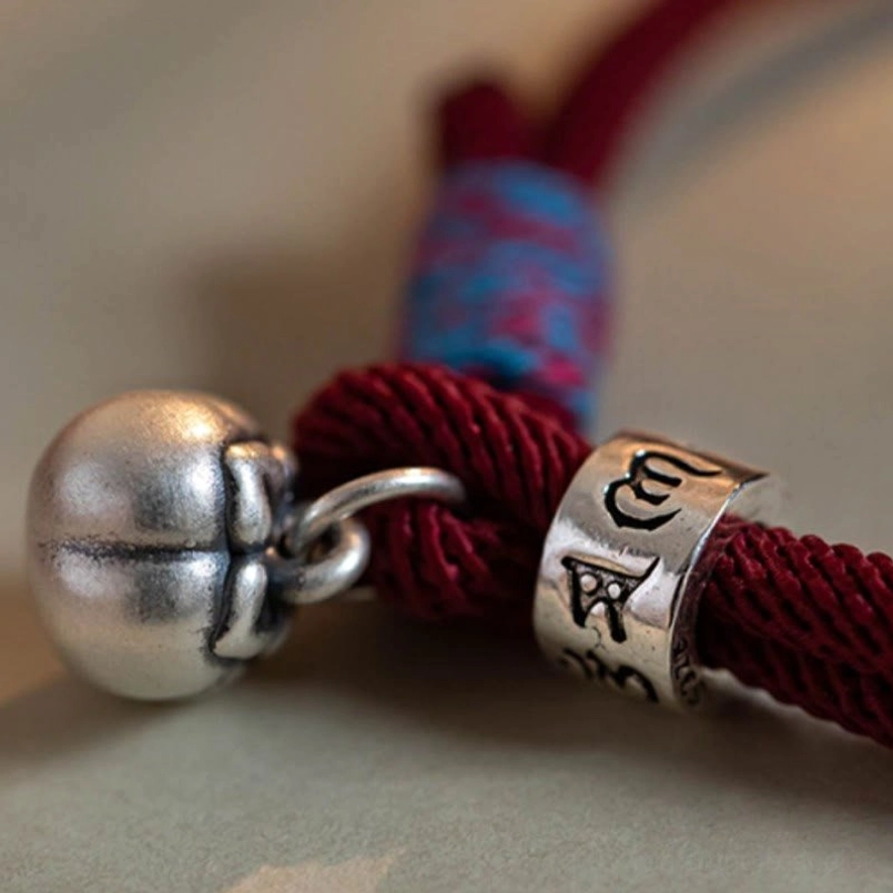 Close-up of Tibetan bracelet silver persimmon bell and engraved mantra bead charm