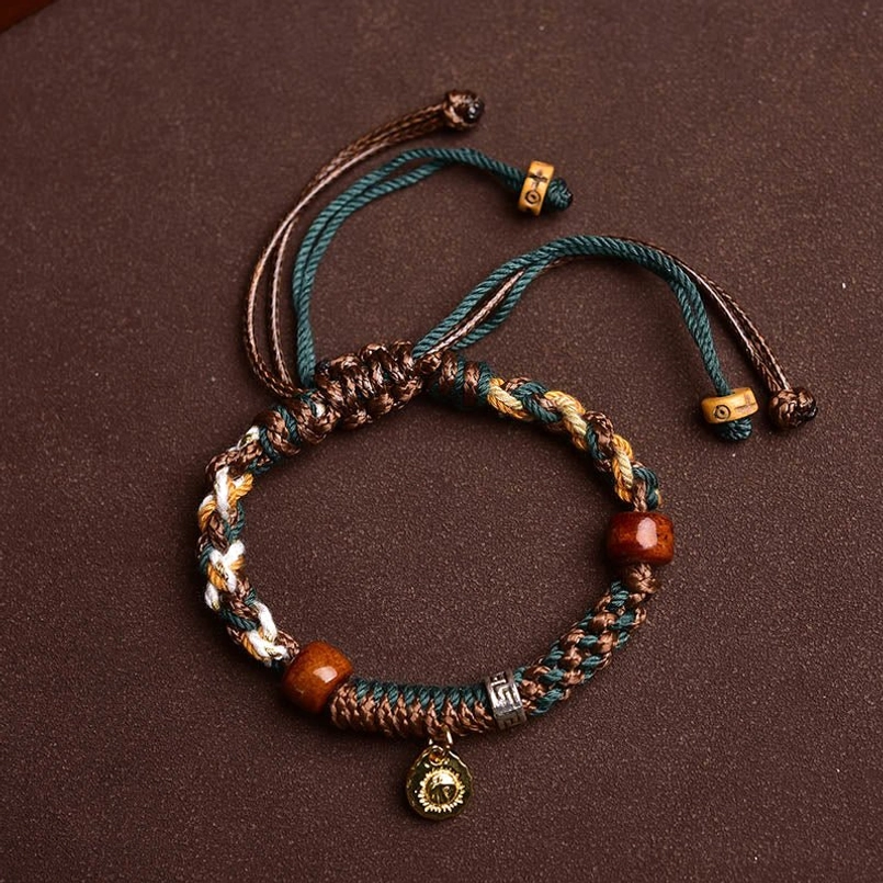 Tibetan style woven red string bracelet with reddish brown bone beads and metal pendant