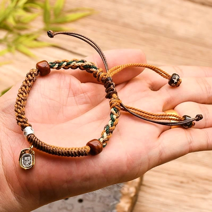 Tibetan woven Zakiram wealth protection bracelet held in palm on wooden table