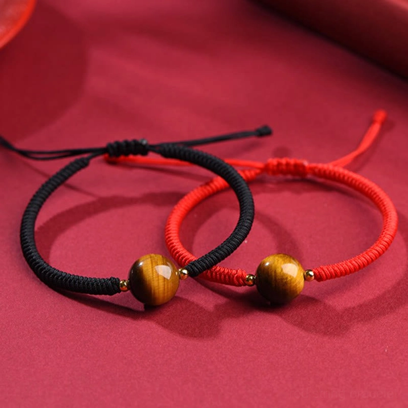 Handmade tiger eye bracelets comparison - red and black braided cord styles on fabric